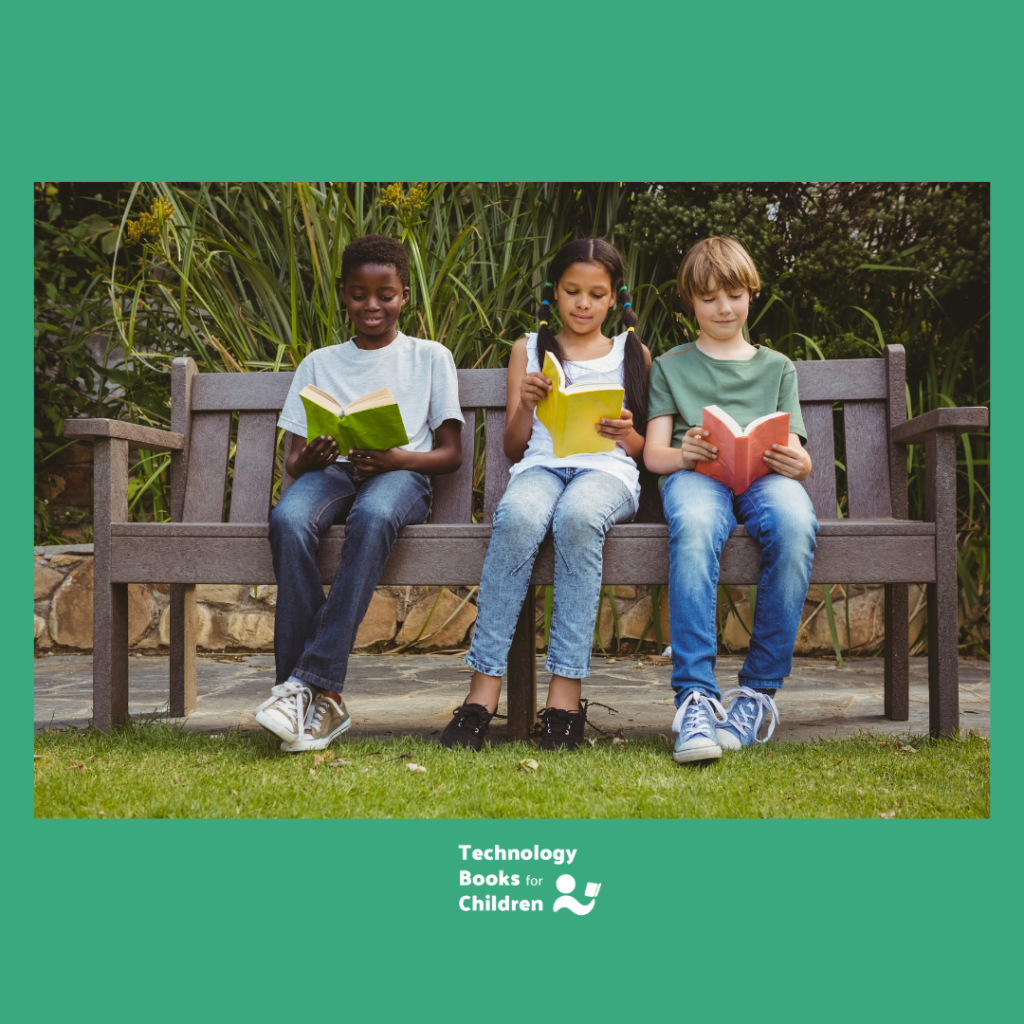 Children sitting on a bench reading technology books